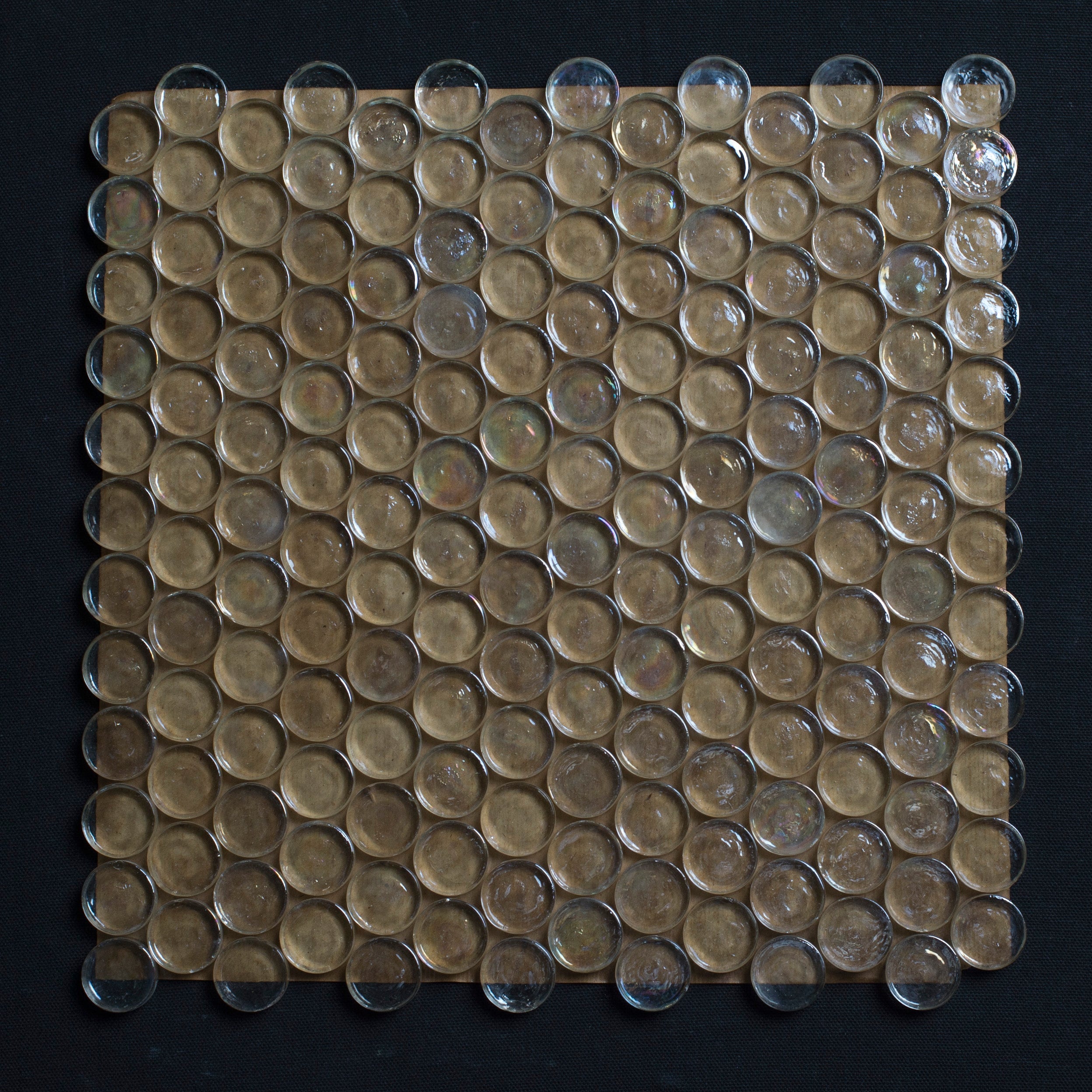 Square tile with circular glass pieces on a black background