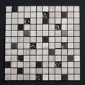 Mosaic tile sample with black and white squares on a dark background